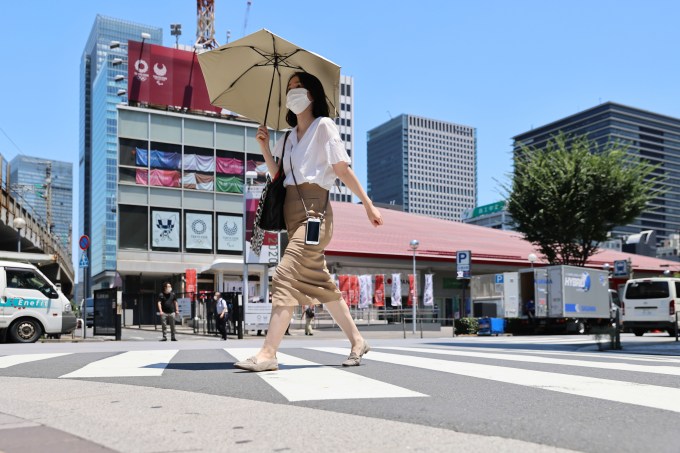 A woman with an umbrella crosses the road in front of Tokyo