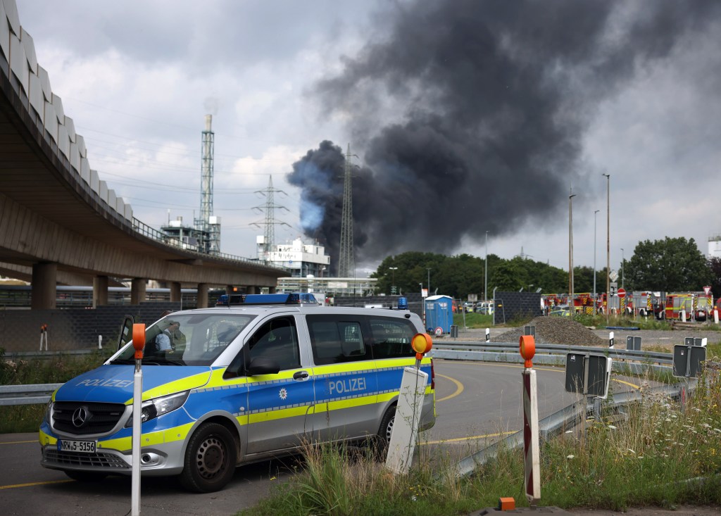 27 July 2021, North Rhine-Westphalia, Leverkusen: A dark cloud of smoke rises above the Chempark. After an explosion, fire brigade, rescue forces and police are currently in large-scale operation, the police explained. Due to the damage, the busy motorway A1 near Leverkusen has been closed. Photo: Oliver Berg/dpa (Photo by Oliver Berg/picture alliance via Getty Images)