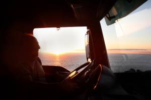 truck driver silhouette with sunset and ocean in background