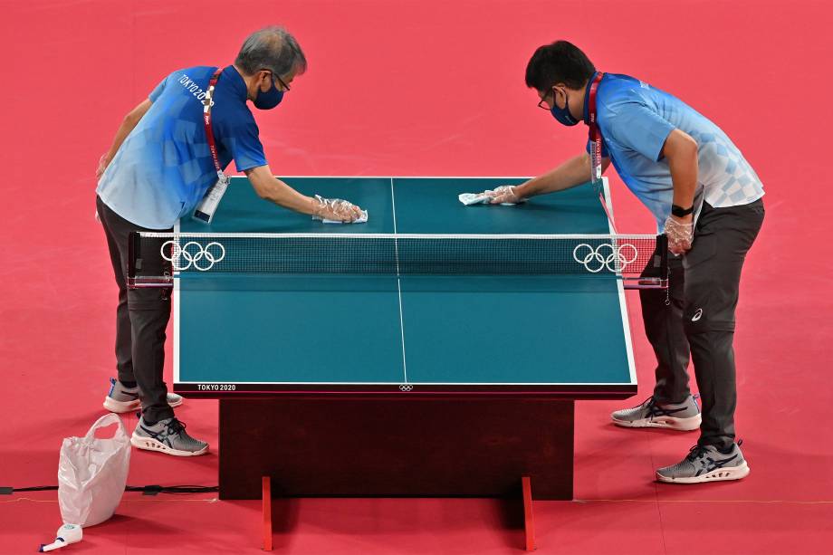 Voluntários fazem limpeza durante os treinos das equipes de tênis de mesa no Tokyo Metropolitan Gymnasium -