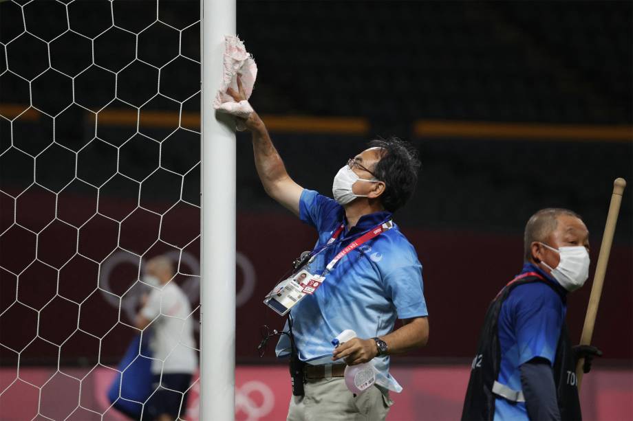 Voluntário desinfeta gol no Estádio Sapporo Dome após a partida entre Egito e Espanha -