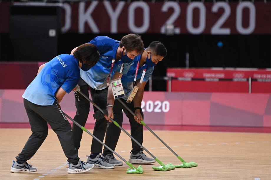 Voluntários limpam o chão durante a partida de handebol feminino entre Brasil e Rússia -