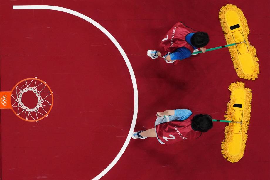 Voluntários secam a quadra durante a partida de basquete feminino entre França e Japão -