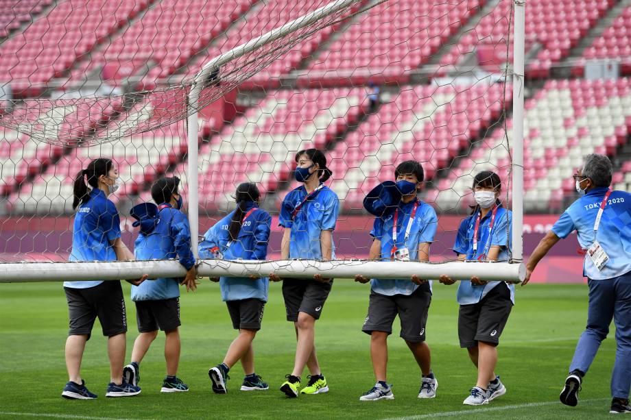 Voluntários carregam gol antes da partida de futebol feminino entre Estados Unidos e Austrália -