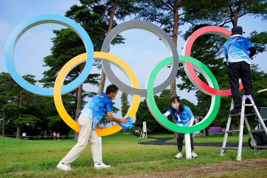 Voluntários limpam os anéis Olímpicos no Kasumigaseki Country Club -