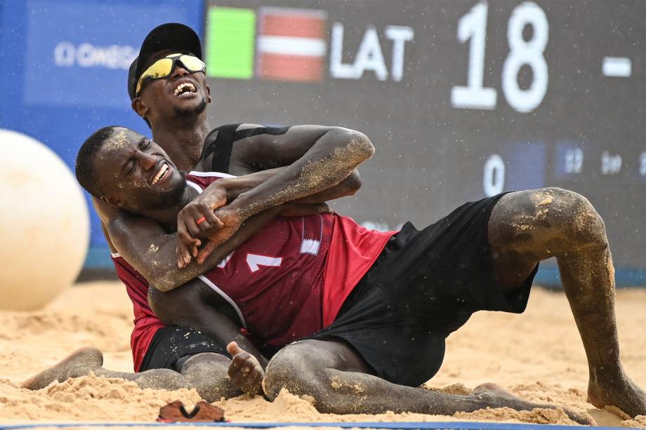 Ahmed Tijan (atrás) e Cherif Younousse , do Qatar, comemoram ao ganhar o bronze na partida e vôlei de praia contra a Letônia -