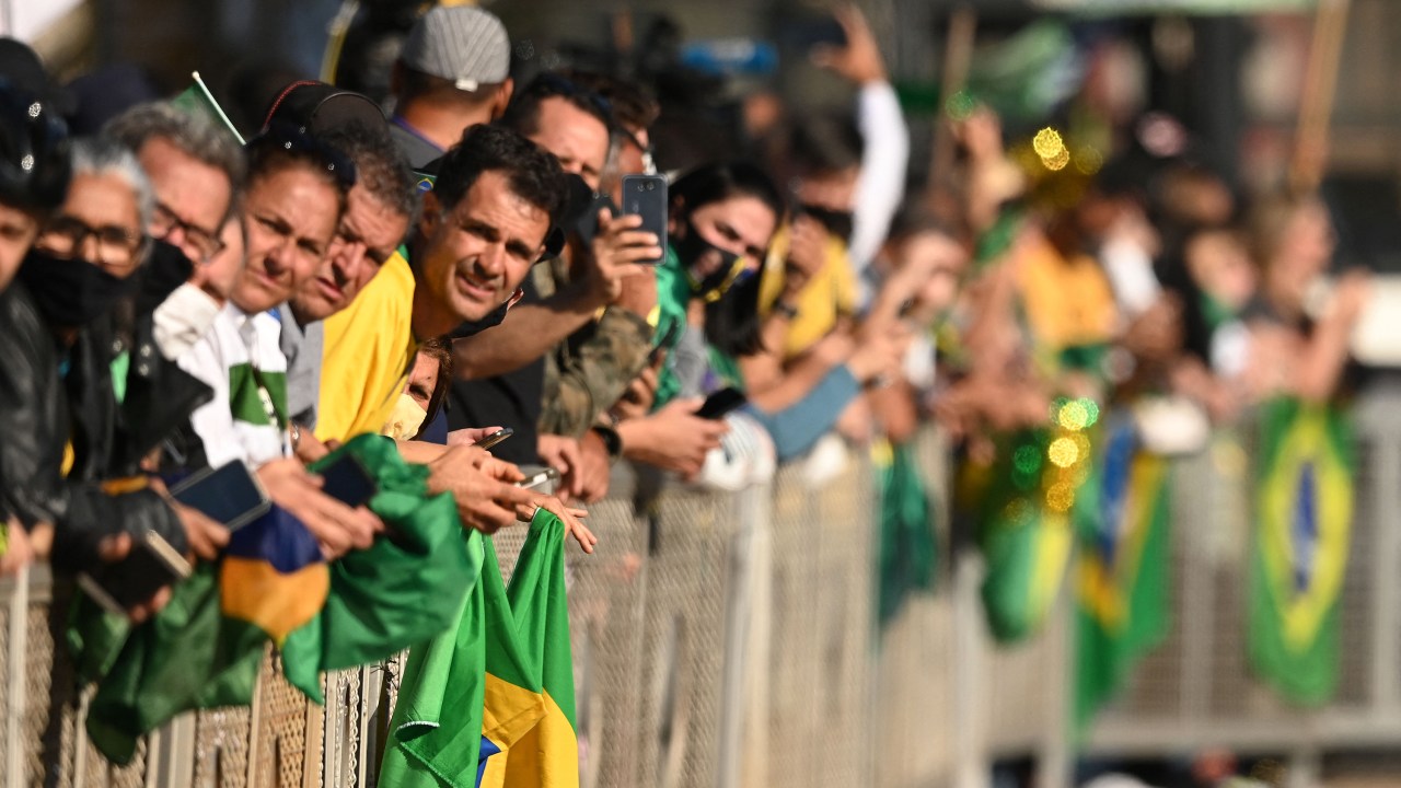 Supporters of Brazilian President Jair Bolsonaro attend a military vehicles parade in front of the Planalto Palace in Brasilia, on August 10, 2021. - Bolsonaro is accused of using the armed forces for a show of force to intimidate National Congress, where a bill is being debated to modify the electronic voting system. (Photo by EVARISTO SA / AFP)