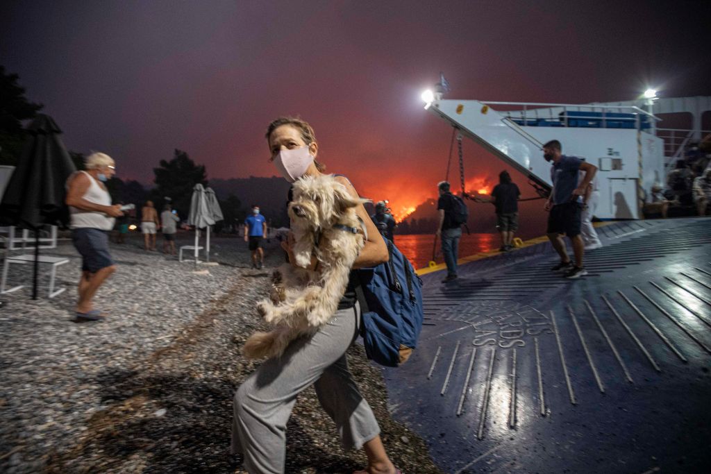 People board a ferry prior to an evacuation as a wildfire approaches the seaside village of Limni, on the island of Evia, Greece, on August 6, 2021. (Photo by STR/NurPhoto via Getty Images)