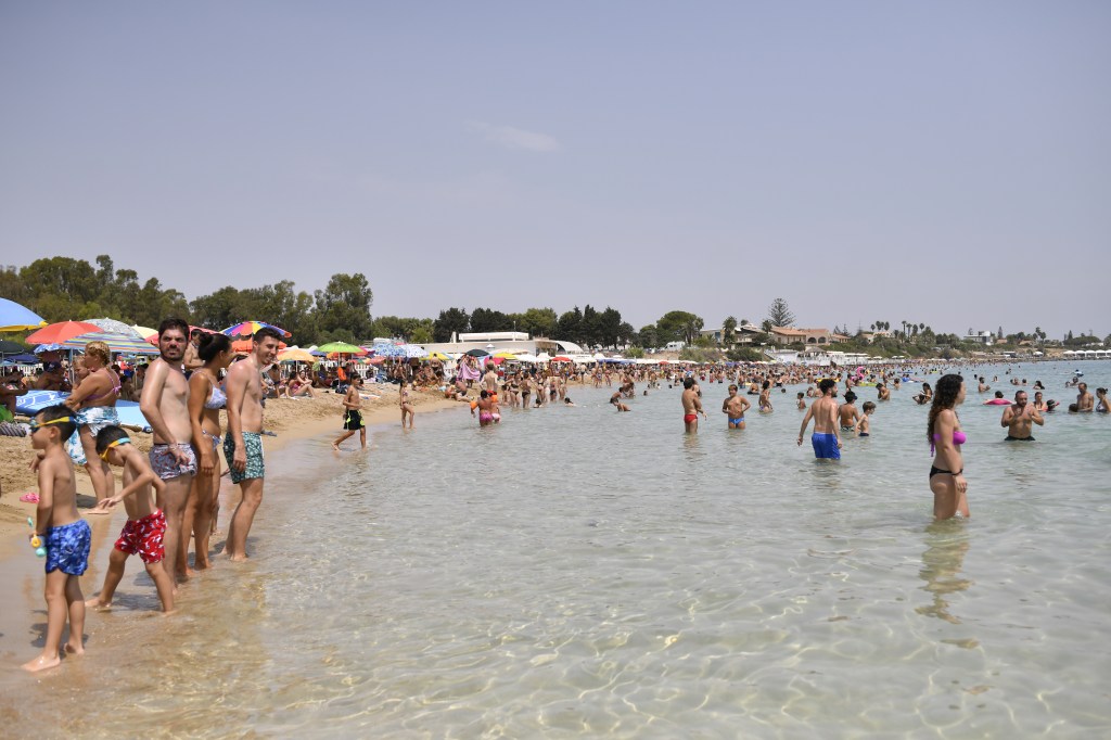 Moradores de Arenella, na Sicília, se refrescam em praia em dia termômetros a quase 50ºC