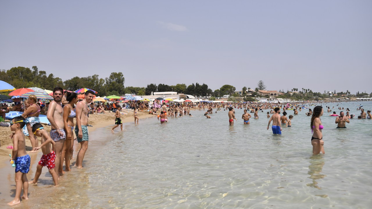 Moradores de Arenella, na Sicília, se refrescam em praia em dia termômetros a quase 50ºC