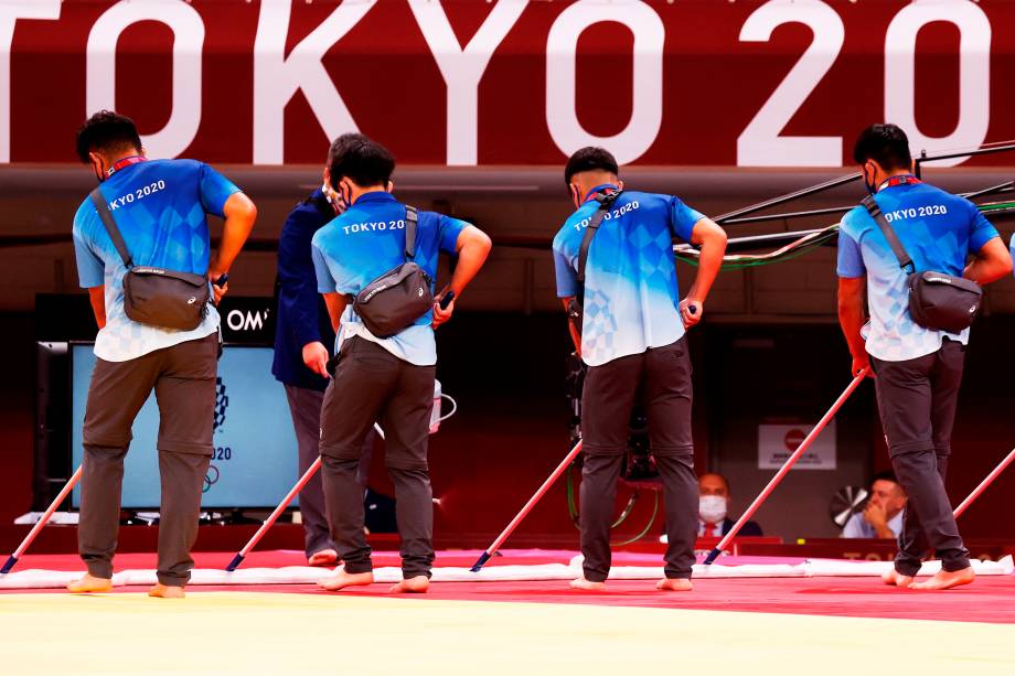 Voluntários limpam o chão antes das competições de judô na Nippon Budokan Arena -