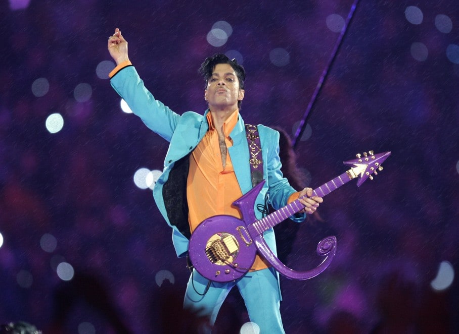 O cantor Prince no show do intervalo do Super Bowl, tocando uma guitarra com o formato de seu nome