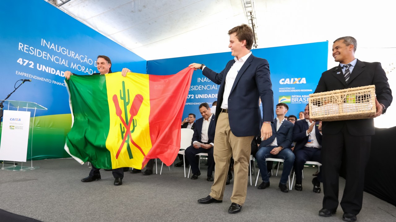 O prefeito de Petrolina (PE), Miguel Coelho, entrega a bandeira da cidade ao presidente Jair Bolsonaro, durante evento em maio de 2019