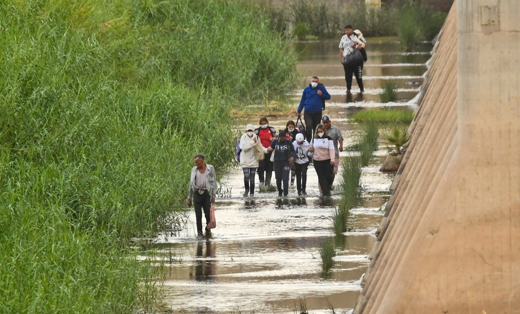 Um grupo de pessoas cruza a fronteira México-EUA.