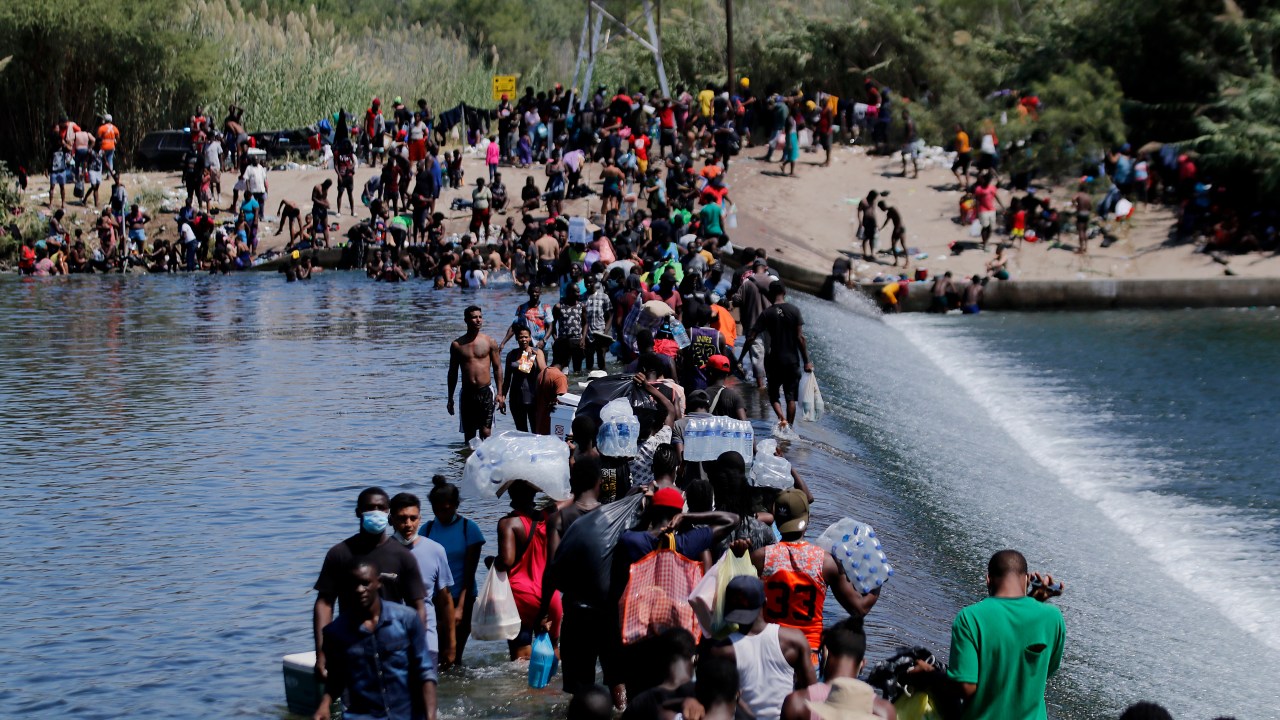 Imigrantes cruzam a fronteira do México com os Estados Unidos neste sábado (18)