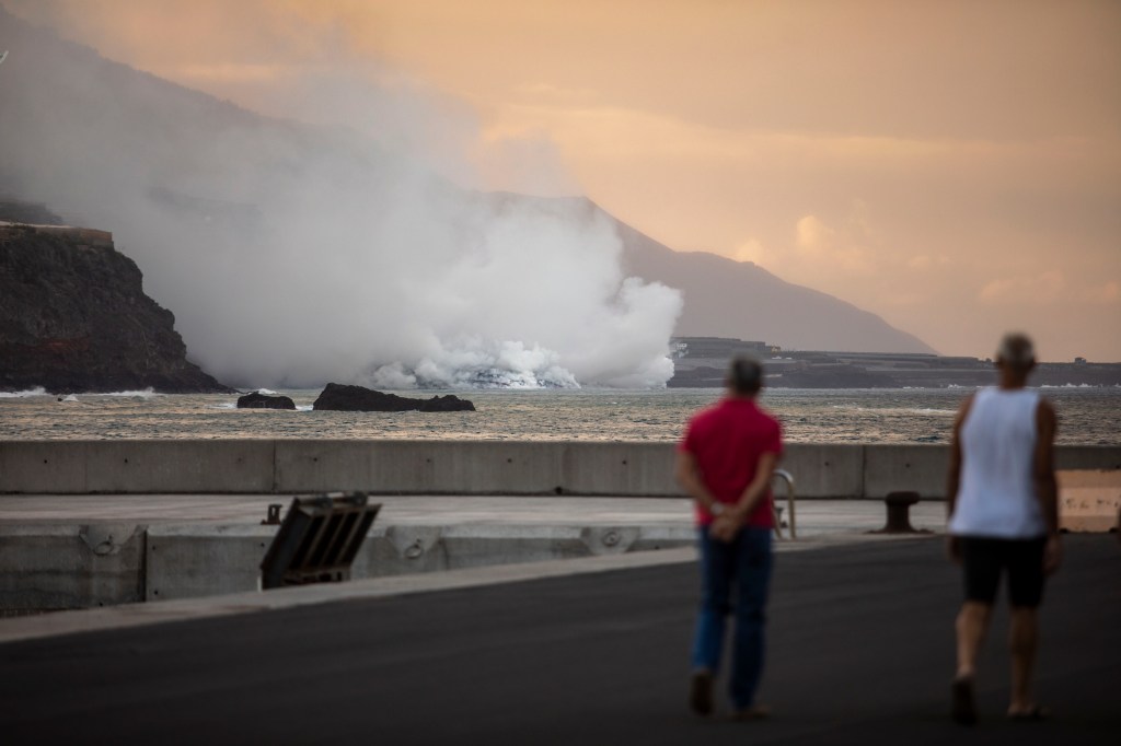 Pessoas observam nuvem de fumaça formada pelo contato da lava do vulcão Cumbre Vieja com o oceano em La Palma - 29/09/2021