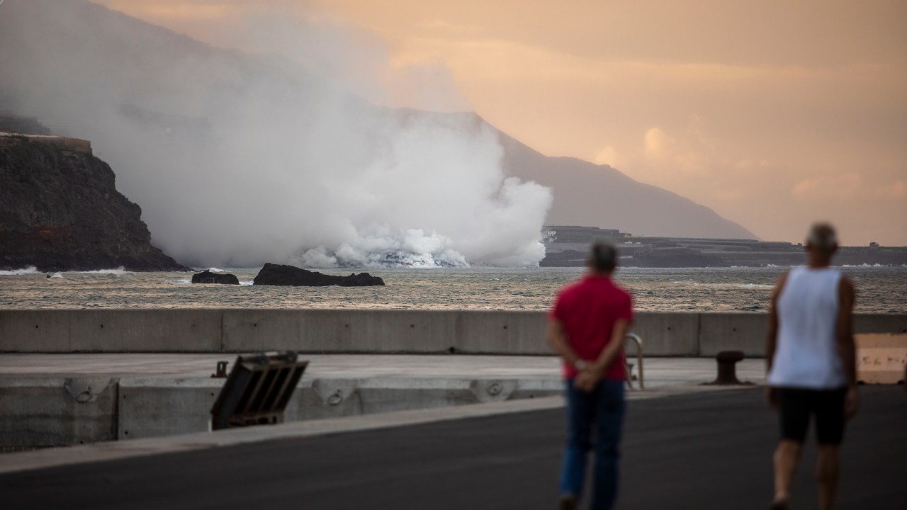 Pessoas observam nuvem de fumaça formada pelo contato da lava do vulcão Cumbre Vieja com o oceano em La Palma - 29/09/2021