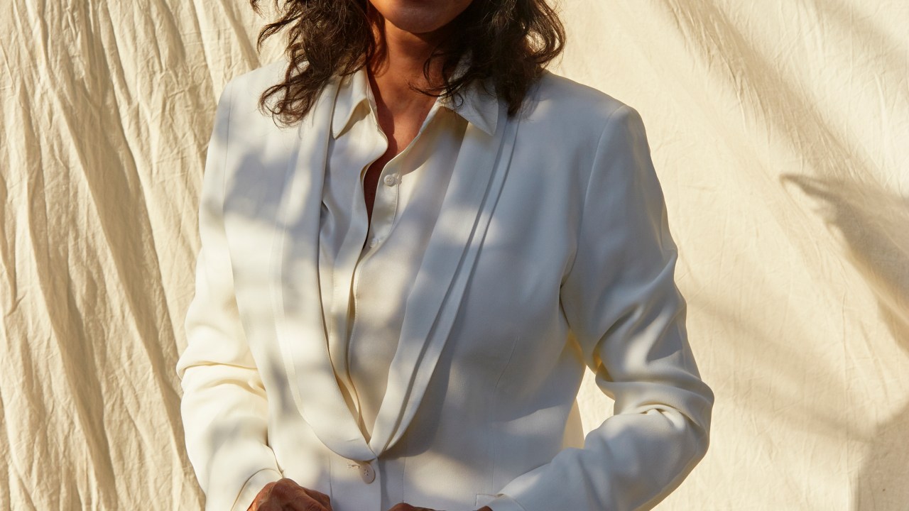A imagem mostra a cantora Simone, de blazer branco