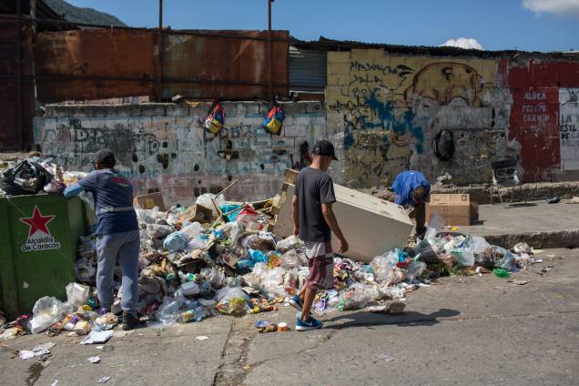 Pessoas procuram itens para venda e alimentação em uma lixeira na favela de Antimano, em Caracas -