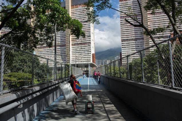 Um vendedor ambulante caminha em uma ponte de pedestres na favela de San Agustin, em Caracas -