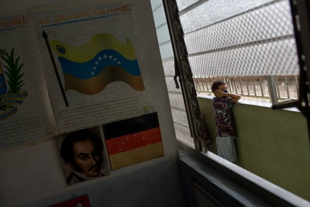 Uma criança observa pela varanda de uma escola fechada, na favela de Petare, em Caracas -