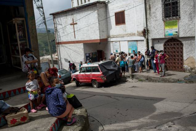 Pessoas esperam na fila do lado de fora de uma ONG na favela de Petare, em Caracas -