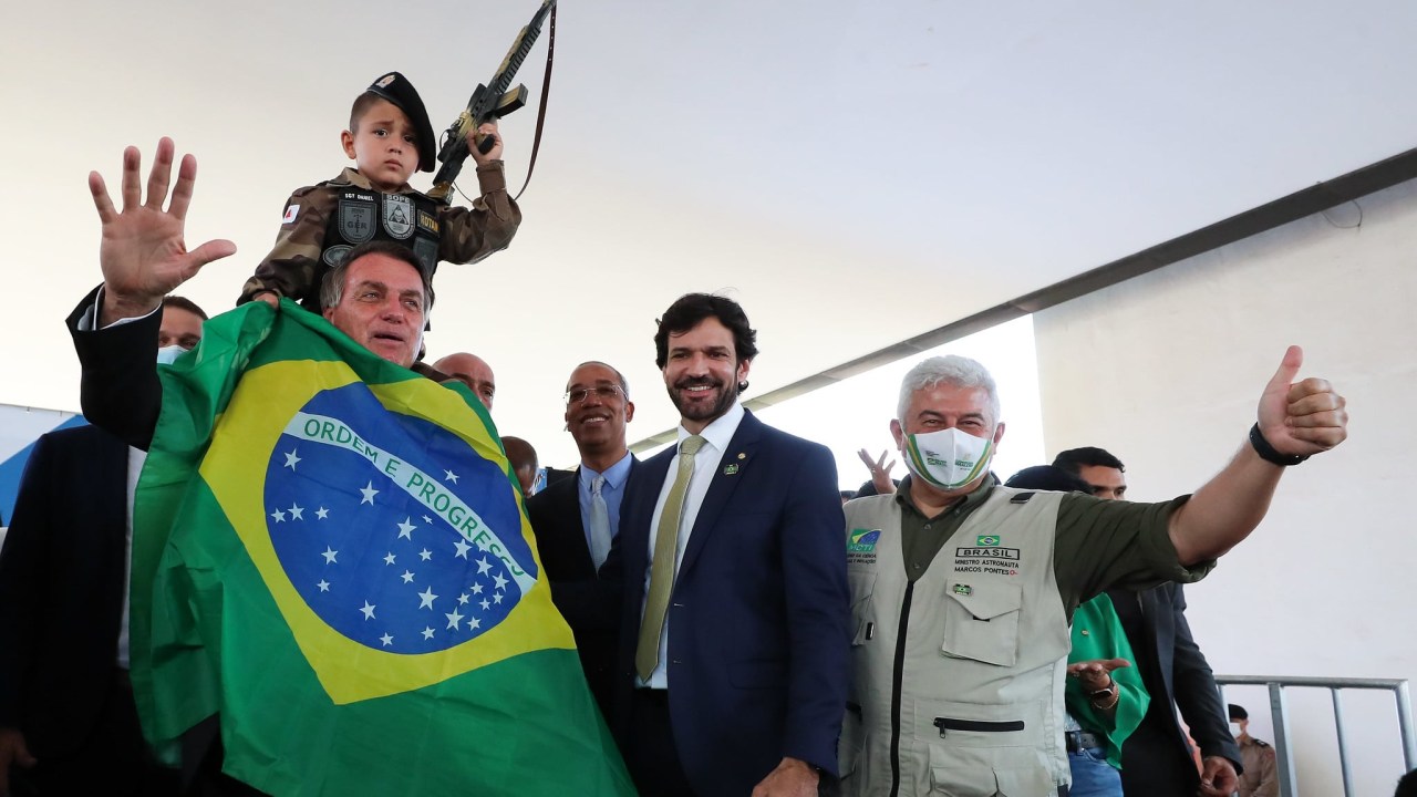 O presidente Jair Bolsonaro posa com criança empunhando uma arma de brinquedo em evento em Belo Horizonte