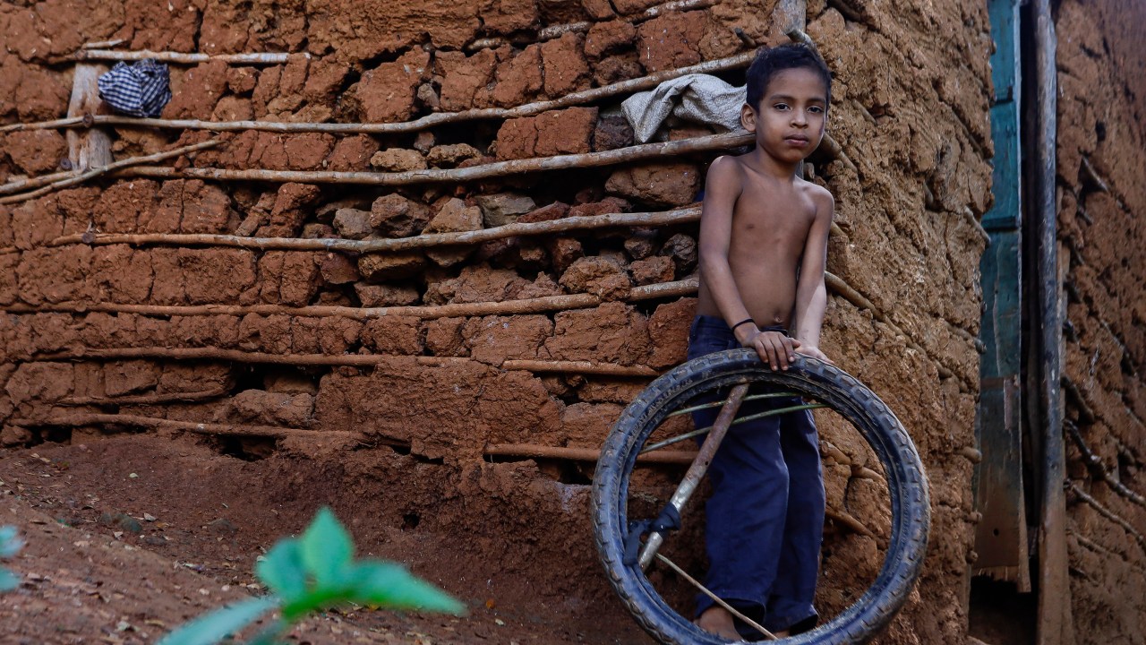Criança brinca com pneu de motocicleta em frente a sua casa no bairro rural de Tocorón, no estado de Miranda -