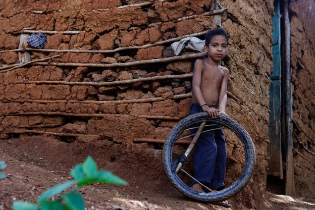Criança brinca com pneu de motocicleta em frente a sua casa no bairro rural de Tocorón, no estado de Miranda -