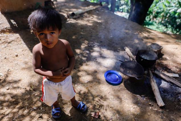 Uma criança espera que sua comida preparada em uma fogueira improvisada ao lado de sua casa, no bairro rural de Tocorón -