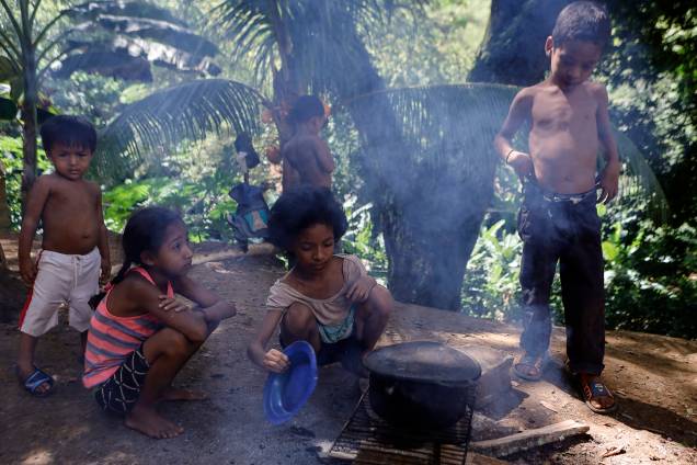 Crianças cozinham em uma fogueira improvisada ao lado de sua casa no bairro rural de Tocorón, no estado de Miranda -
