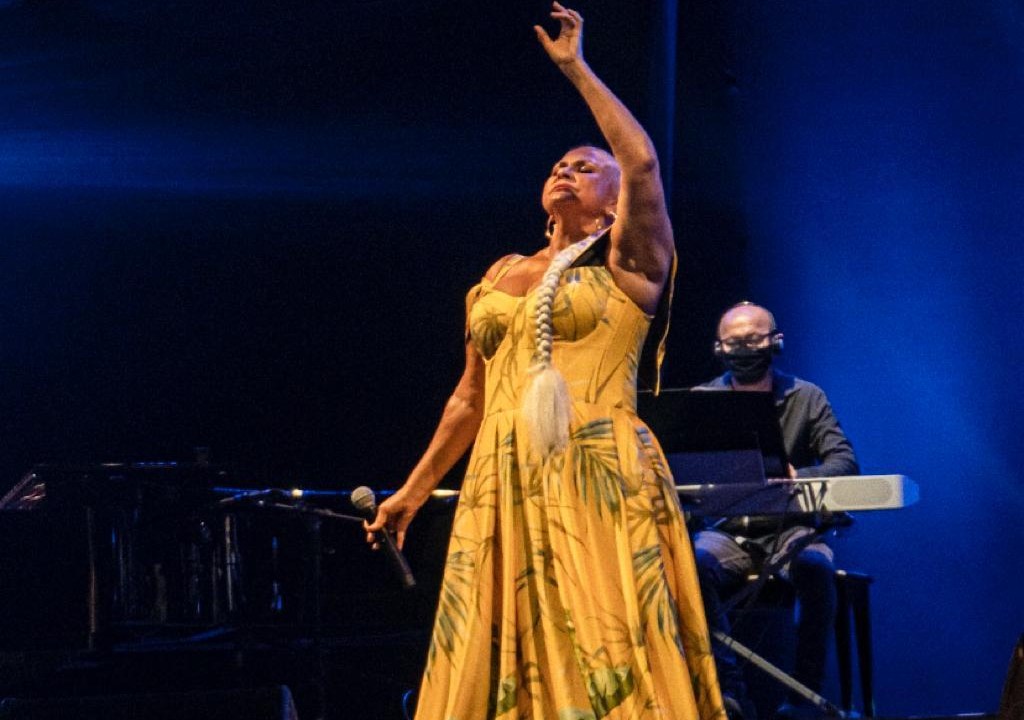A imagem mostra Fafá de Belém no palco, de vestido amarelo