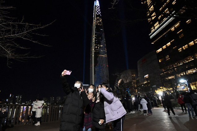 Mulheres tiram selfie em frente ao prédio Lotte World pouco antes da virada em Seul, na Coreia do Sul
