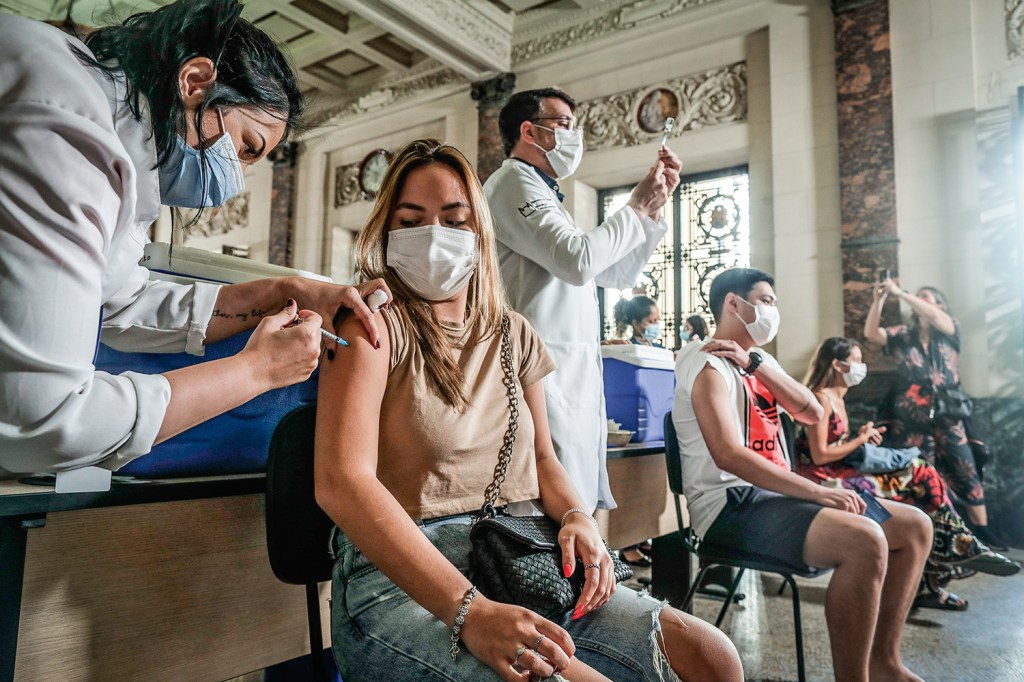 AME9498. RIO DE JANEIRO (BRASIL), 18/08/2021.- Una persona recibe una dosis de la vacuna contra covid-19 hoy, en el Palácio Tiradentes, antigua sede de la Asamblea Legislativa, en Río de Janeiro (Brasil). Brasil volvió a registrar más de 1.000 muertes en un solo día asociadas al coronavirus, pero mantiene la desacelerada de la pandemia evidenciada en las últimas semanas con los promedios más bajos del año, mientras avanza la vacunación a la población, según las cifras divulgadas por el Ministerio de Salud. EFE / André Coelho