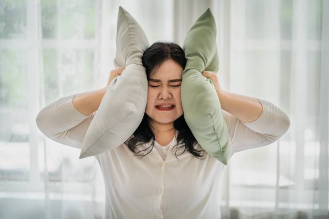 Woman covering her ears with a pillow, the concept does not want to hear things. affecting oneself
