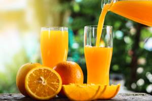 Hand Pouring Orange Juice On Glasses