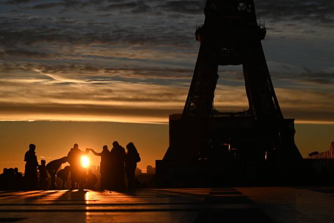 Turistas assistem ao sol nascer próximo à Torre Eiffel