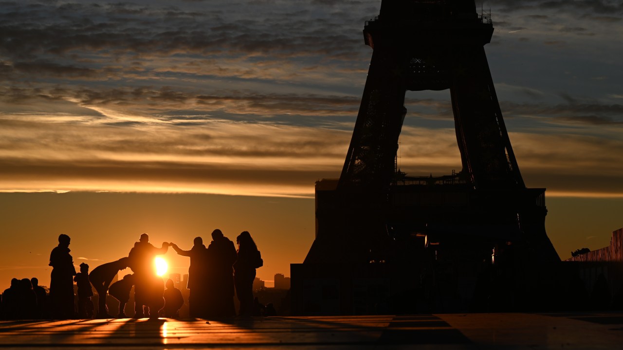 Turistas assistem ao sol nascer próximo à Torre Eiffel neste dia 1º de janeiro de 2022