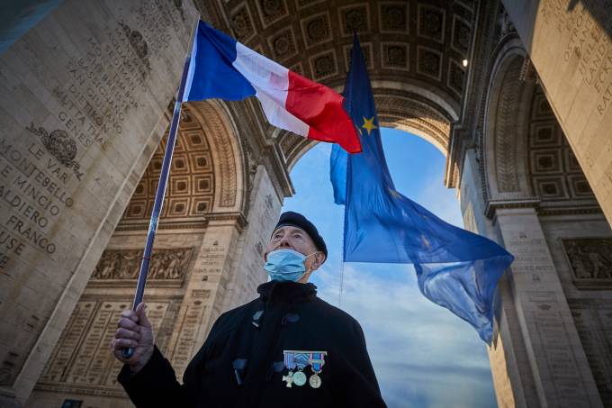 No vigésimo aniversário da União Europeia, homem veterano de guerra exibe bandeira francesa no Arco do Triunfo, em Paris