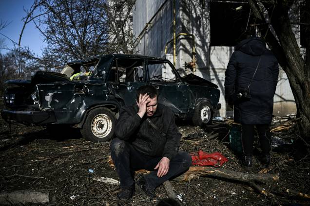Um homem lamenta do lado de fora de seu prédio destruído após bombardeios na cidade de Chuguiv, no leste da Ucrânia -