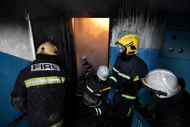 Bombeiros trabalham para conter um incêndio em prédio após bombardeios na cidade de Chuguiv, no leste da Ucrânia -
