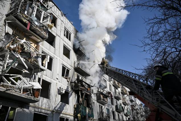 Bombeiros trabalham em um incêndio em um prédio após bombardeios na cidade de Chuguiv, no leste da Ucrânia -