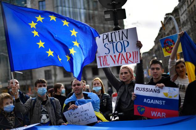 Manifestantes seguram cartazes com os dizeres "Putin, pare a guerra" e bandeiras da União Europeia e da Ucrânia durante um protesto realizado em Barcelona -