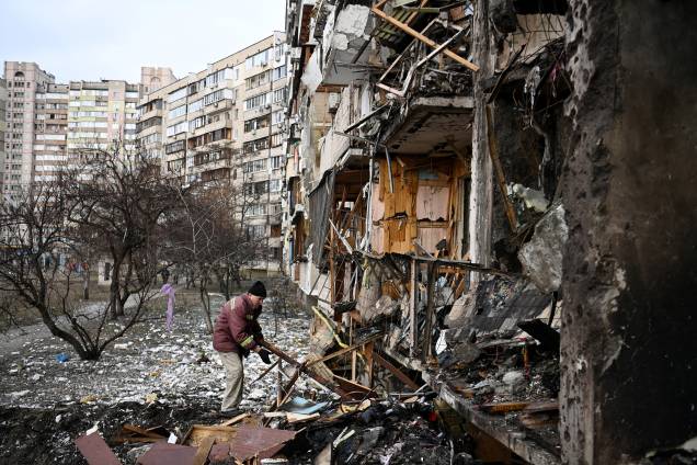 Um homem limpa os destroços em um prédio residencial danificado na rua Koshytsa, em Kiev -