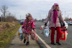 A Ukrainian mother walks with her daughter along the road from the Hungarian-Ukrainian border crossing near Beregsurany, Hungary, some 300 km from the Hungarian capital on February 25, 2022, as Ukrainian citizens have started to flee the conflict in their country one day after Russia launched a military attack on neighbouring Ukraine. - As Ukraine braces for a feared Russian invasion, its EU member neighbours are making preparations for a possible influx of hundreds of thousands or even millions of refugees fleeing military action. (Photo by ATTILA KISBENEDEK / AFP)