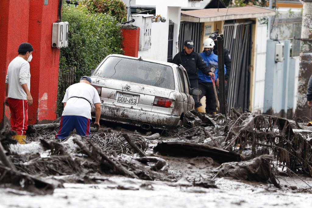 QUITO, ECUADOR - FEBRUARY 01: People and relief organizations clean the streets during the rescue efforts after a landslide was caused by heavy rains on February 1, 2022 in Quito, Ecuador. At least 18 people have been confirmed killed by the landslide caused yesterday by heavy rains in Quito. The floods are considered the heaviest in two decades; authorities report 16 people missing and over 40 injured. (Photo by Felipe Stanley/Agencia Press South/Getty Images)