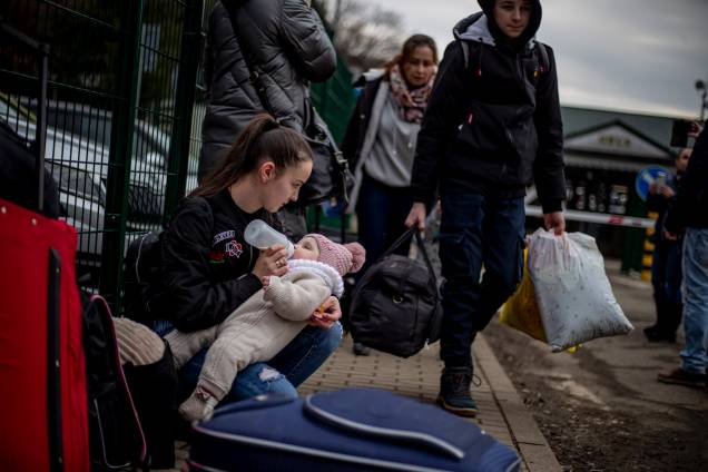 Uma mulher alimenta uma criança enquanto pessoas que fogem da Ucrânia chegam à Eslováquia através da fronteira de Ubla -