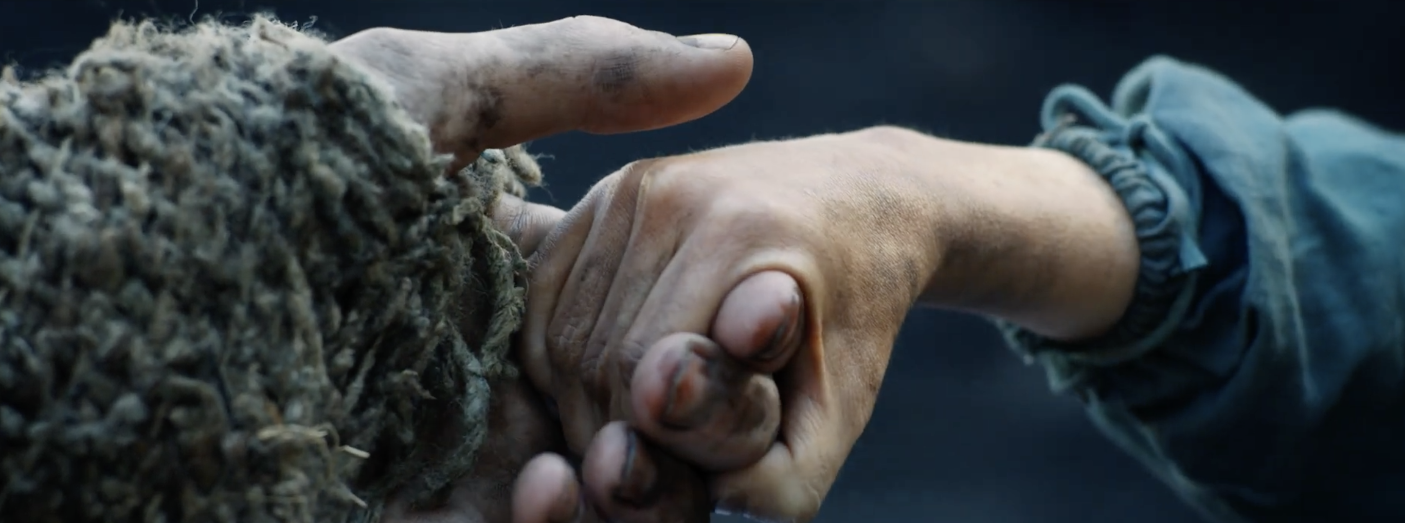 Uma mão pequena segura os dedos de uma mão maior na nova série 'Os Anéis de Poder'