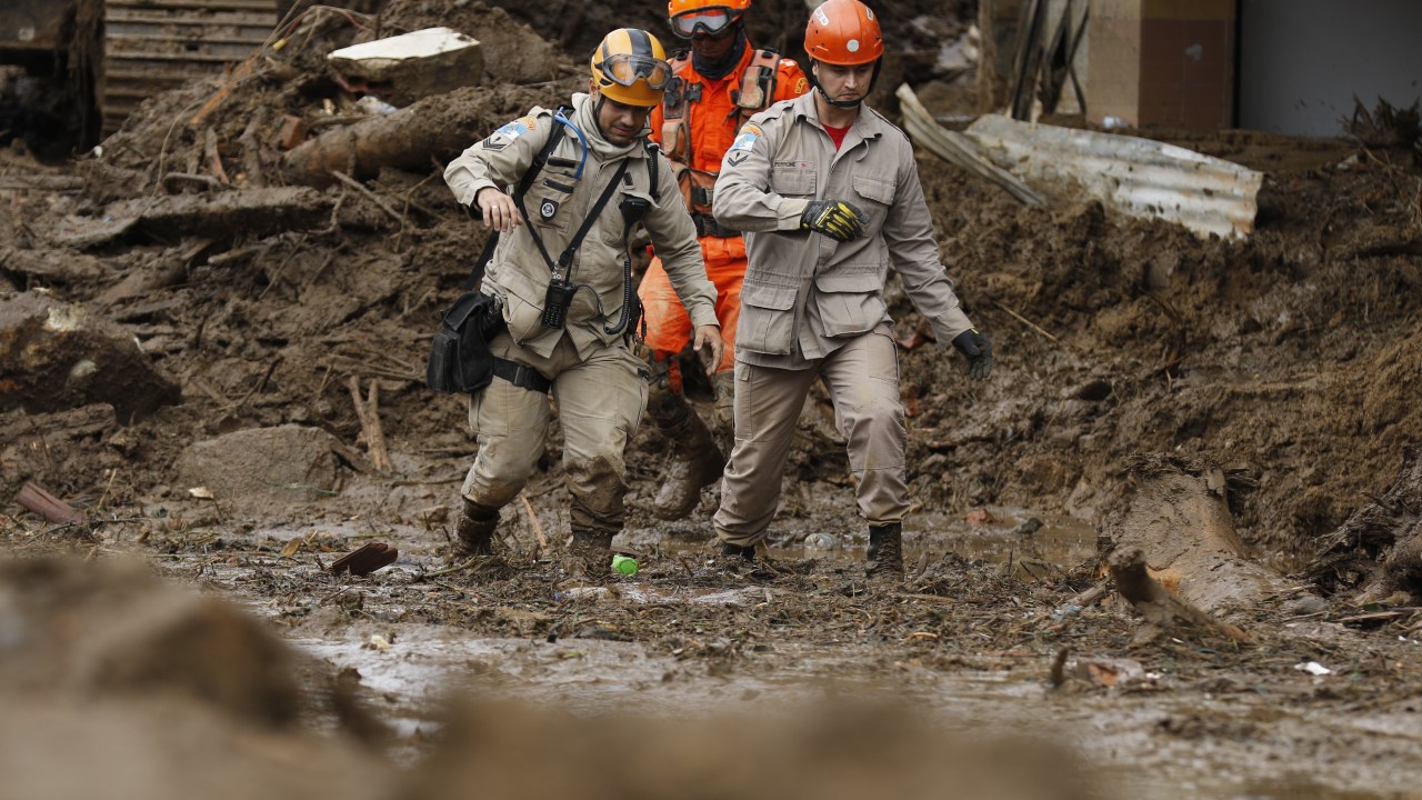 Bombeiros se equilibram sobre a lama acumulada na Rua Teresa, em trabalho de busca nos deslizamentos de terra das chuvas em Petrópolis.