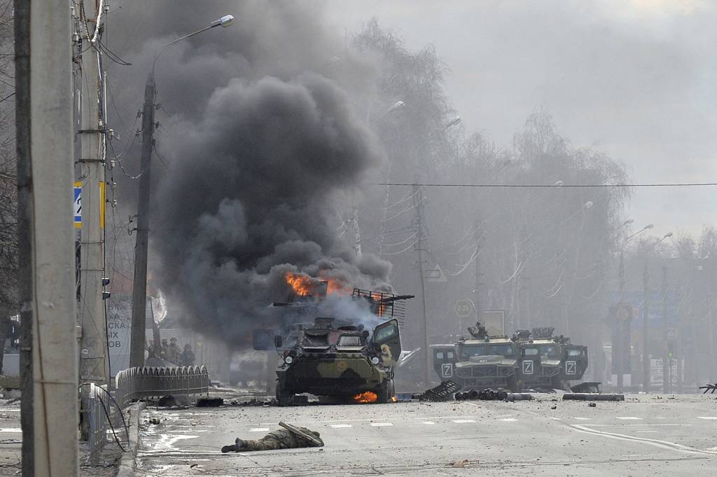 RESISTÊNCIA - Blindado russo em chamas ao lado de soldado morto em Kharkiv: dificuldade inesperada nos primeiros dias -